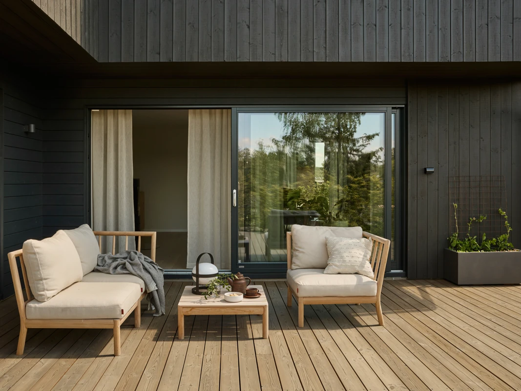 Terrasse beiset med TREBITT Terrassebeis fra Jotun i fargen TREBITT Nordisk Tre, med et sort funkishus i bakgrunnen, beiset med TREBITT Matt Oljebeis i fargen TREBITT Funkissort.