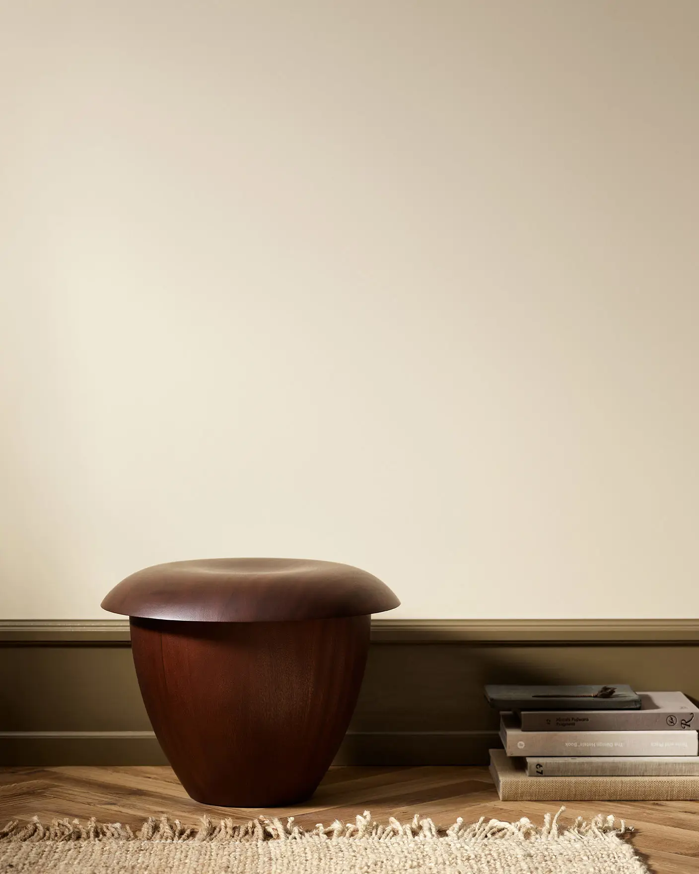 Wooden stool in a minimalist room with wall painted with Jotun 12313 Soft Dunes.